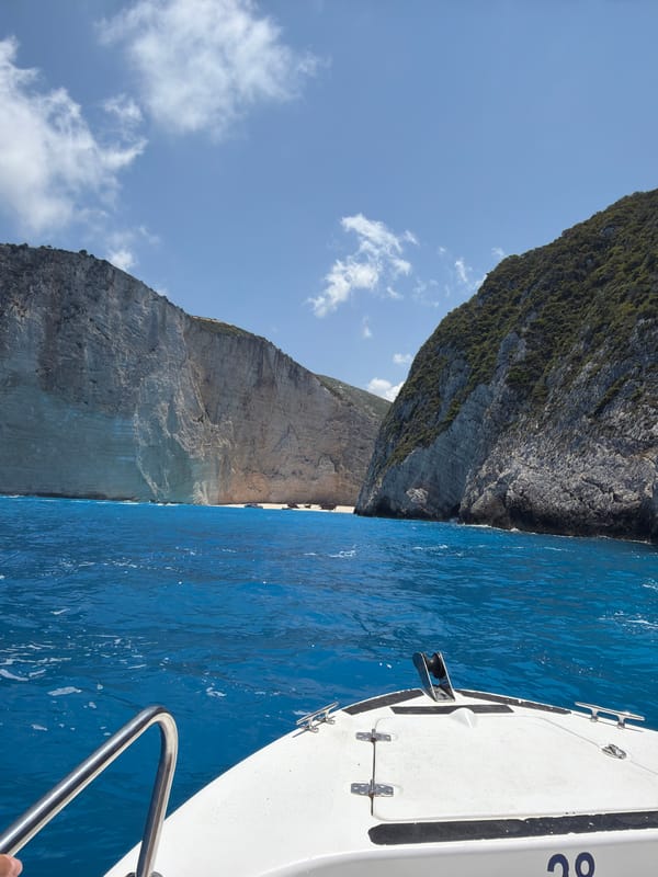 White boat cruises past dramatic cliffs on open ocean