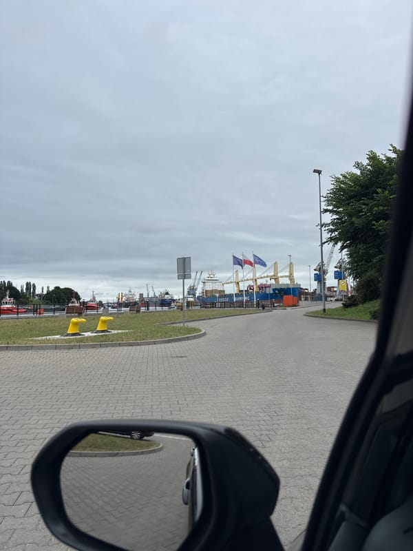 Passing Gdańsk's working harbor with coast guard vessels docked nearby