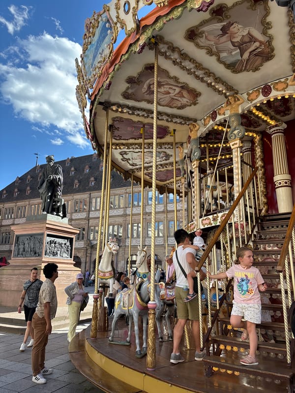 Strasbourg carousel and French bakery display on sunny afternoon