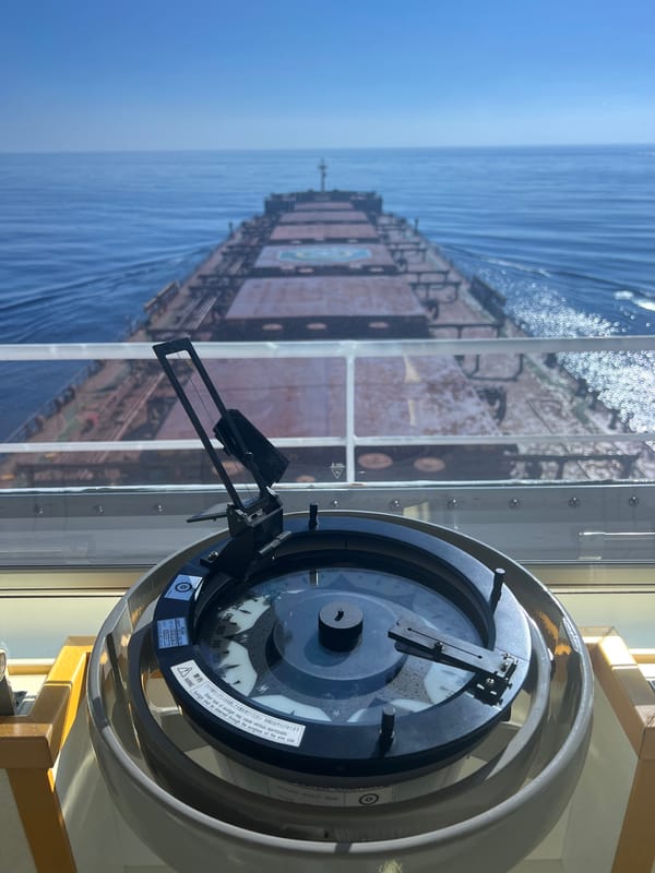 Cargo ship bridge view with compass, open ocean ahead