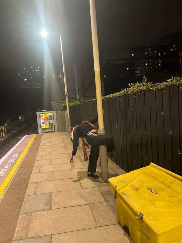 Person lies on London train platform using phone