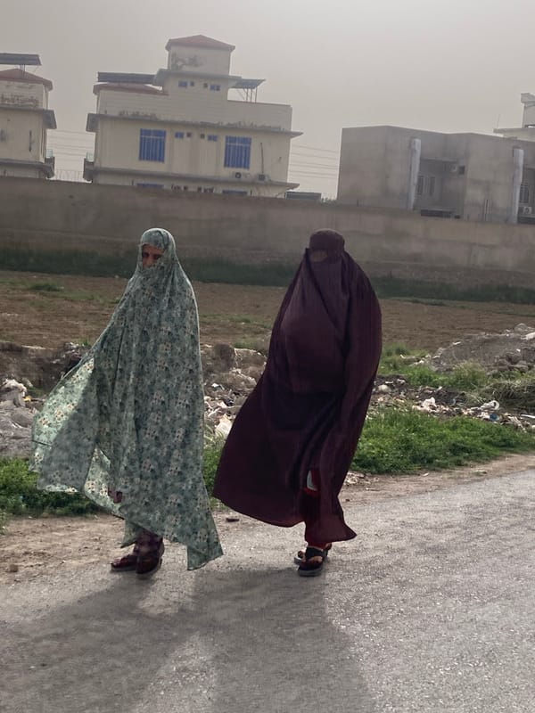 Two women in burqas walk street in Quetta
