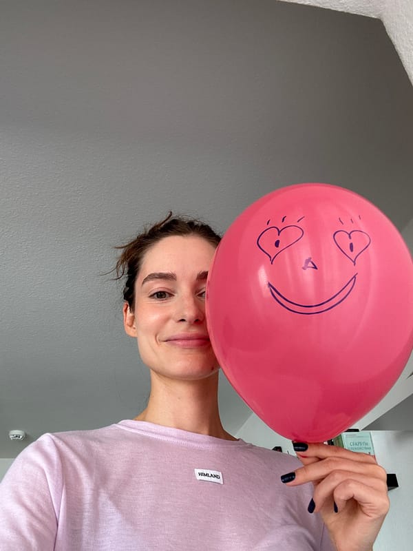 Woman poses with pink balloon against wall in Kiel