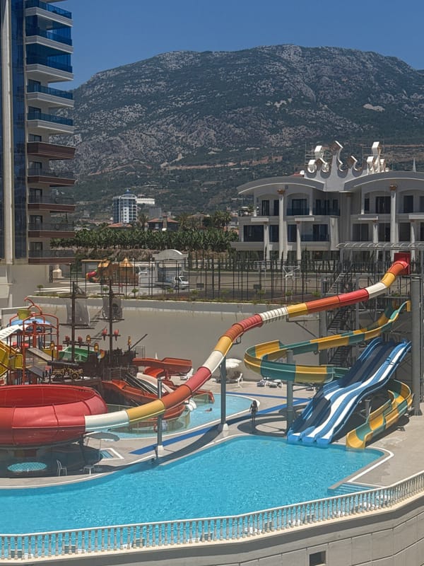 Water park and modern residential complex set against mountain backdrop