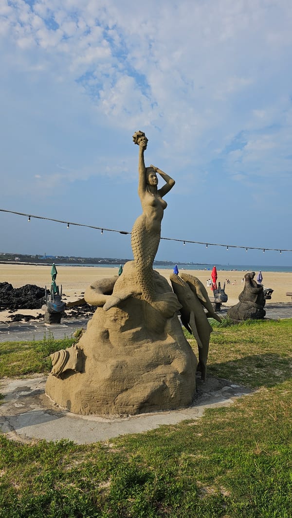 Sculptures and volcanic shoreline at a Seogwipo beach