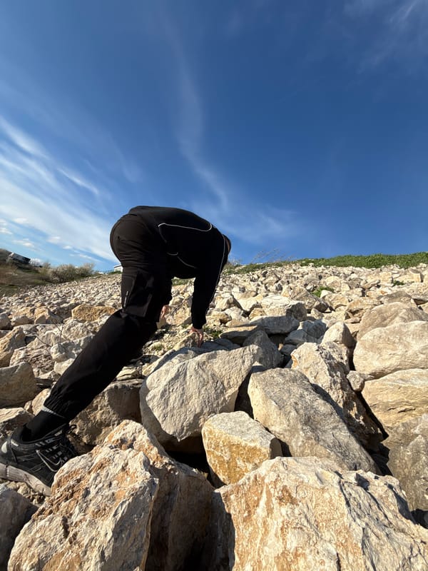Person climbs rocks, rests by lake in Shumen