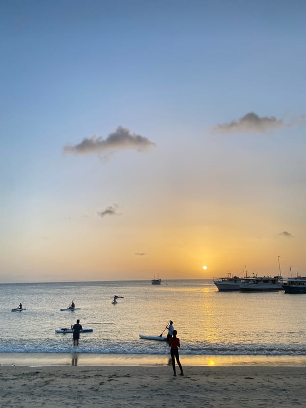 Paddleboarders and beachgoers at sunset in Juan Griego