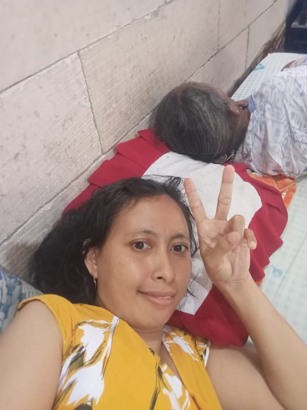 Two people resting on patterned bed in Baron, Indonesia