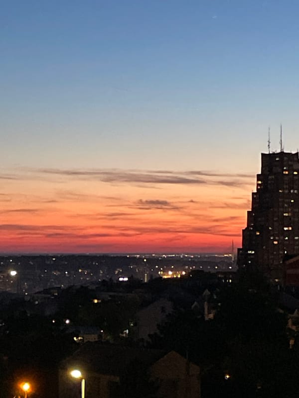 Sunset illuminates construction cranes over Belgrade cityscape