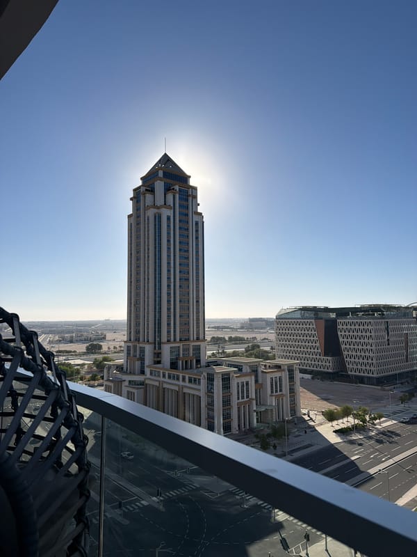 Skyscraper with pointed top dominates sunny city intersection