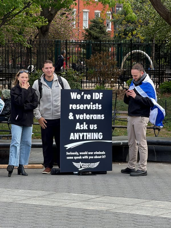 Three people gather near black sign in NYC park