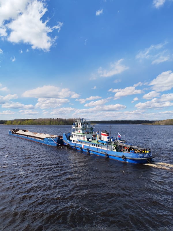 Tugboat pulls loaded cargo barge through Russian waters