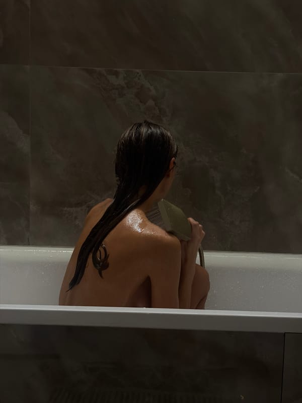Person bathing with handheld shower in Krasnoyarsk bathroom