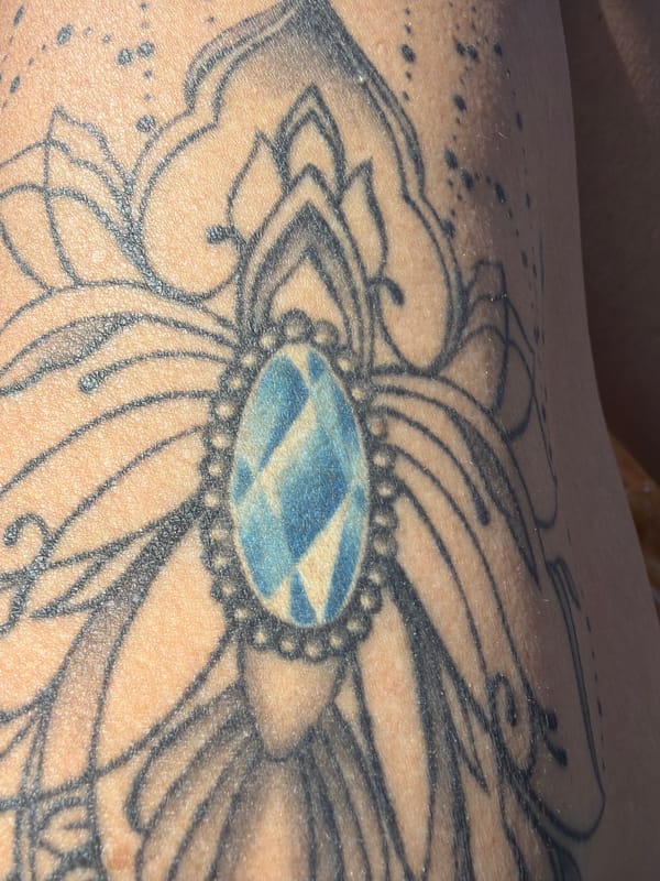 Floral tattoo with blue geometric pattern documented in Al Hadaba