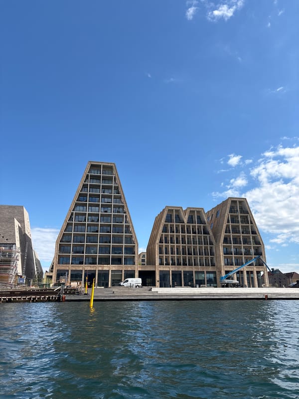 Water bus travels Copenhagen harbor past modern waterfront buildings