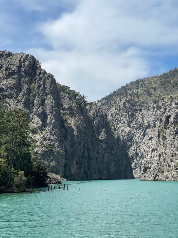 Boat crosses turquoise mountain lake under cloudy skies