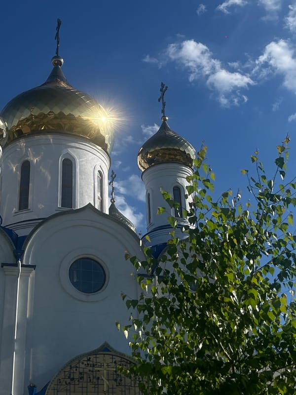 Woman visits Orthodox church gardens in Novopokrovskaya, poses with roses