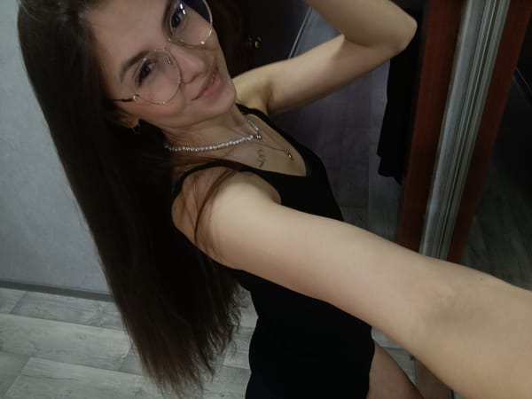 Woman takes mirror selfies indoors wearing glasses, black top