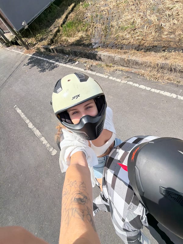 Motorcycle selfie mid-ride, tattooed arm and plaid sleeve in frame