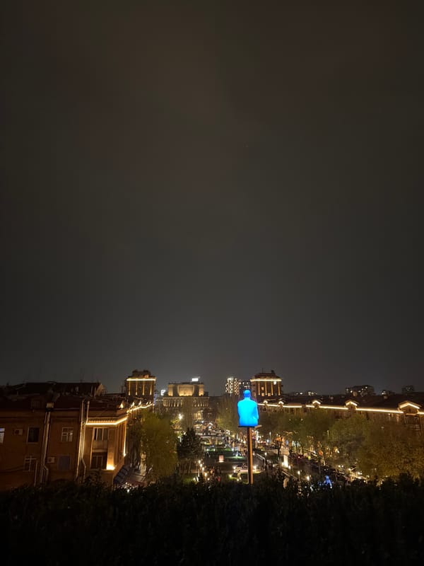 Evening street scene captured in Yerevan with illuminated sculpture