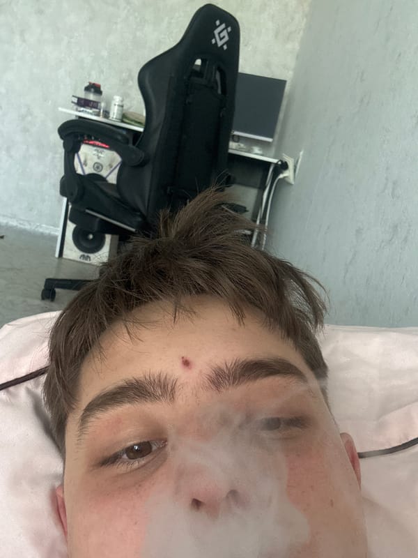 Person with tattoo vaping indoors during early morning hours