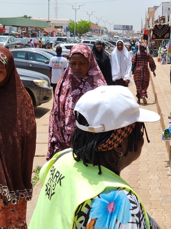 Sunny marketplace scene features people in traditional Islamic dress
