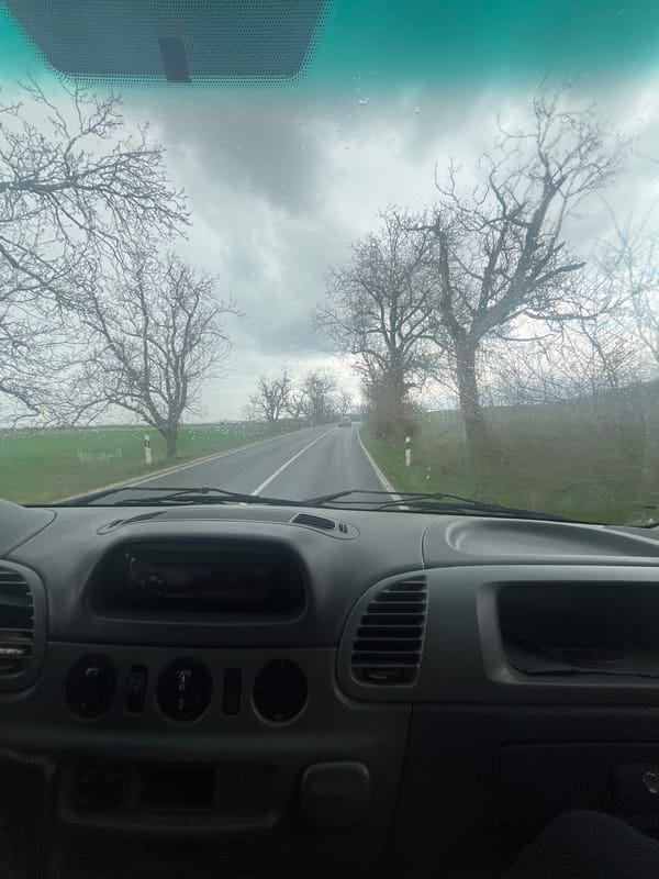 Vehicle travels wet road in overcast Bulgarian countryside
