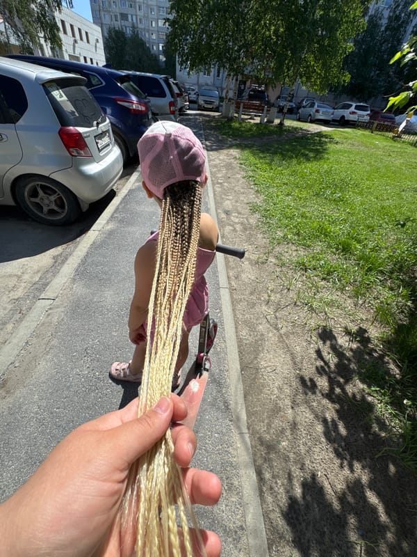 Child plays with dandelions, rides scooter in Megion spring morning