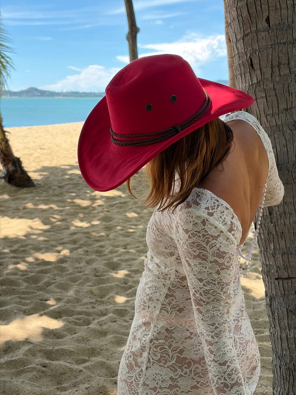 White lace dress and red hat on a Koh Samui beach path