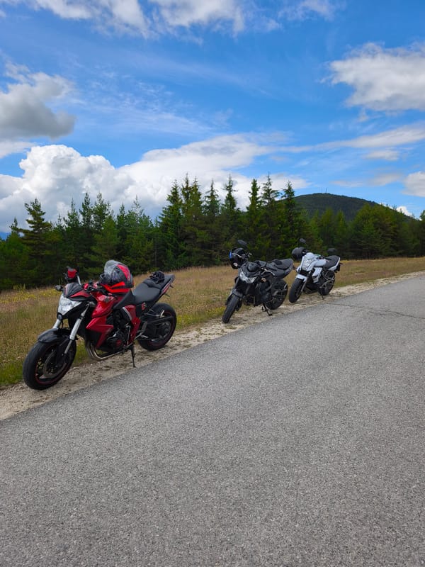 Four motorcycles parked on roadside dirt shoulder