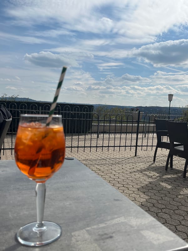Man enjoys orange drink at outdoor table in Saarburg