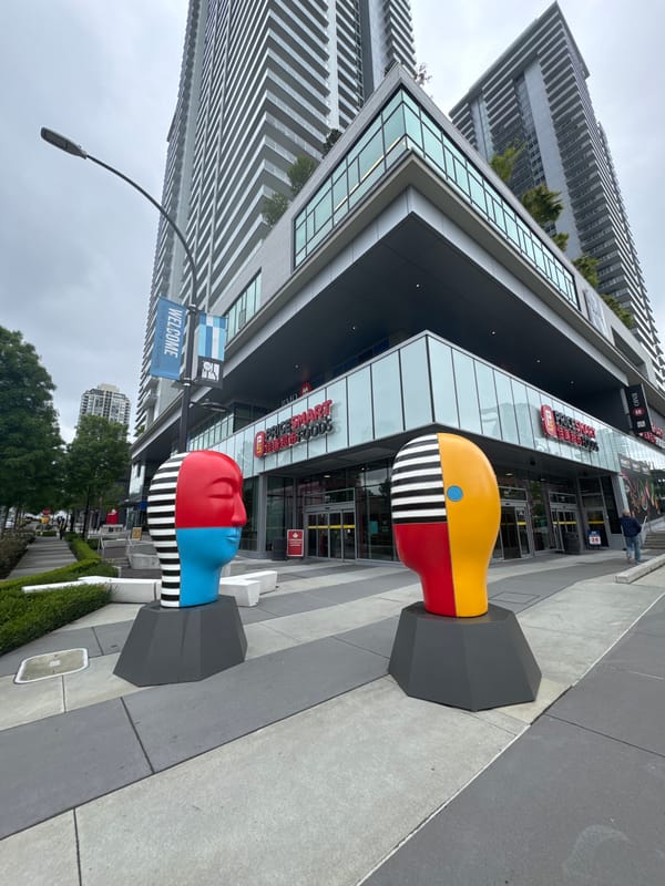 Colorful abstract head sculptures displayed on Burnaby pedestrian pavement
