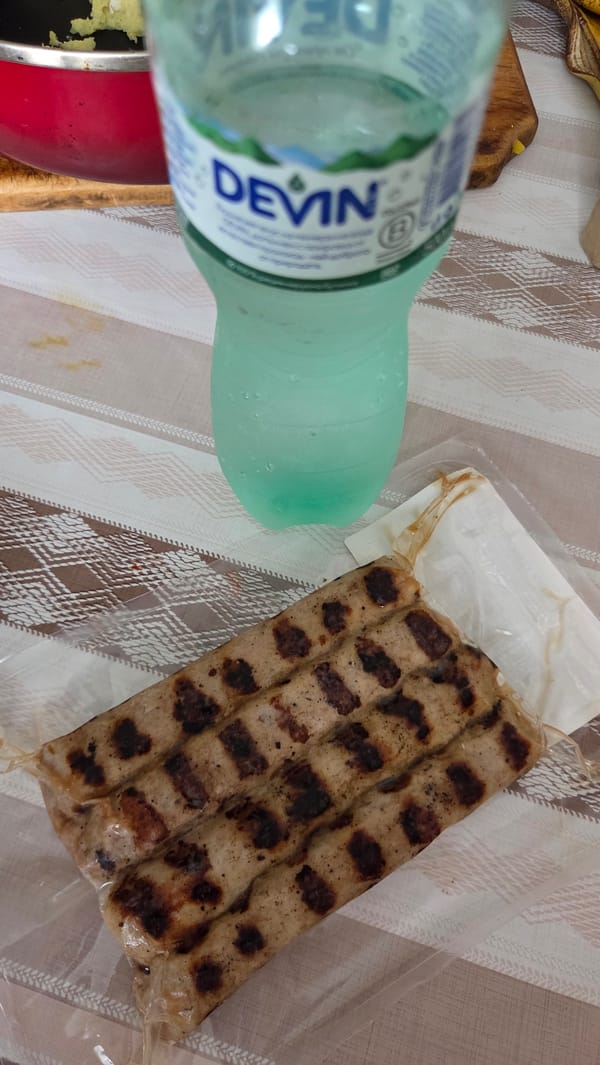 Grilled sausages, mineral water, and a poster-covered cabinet