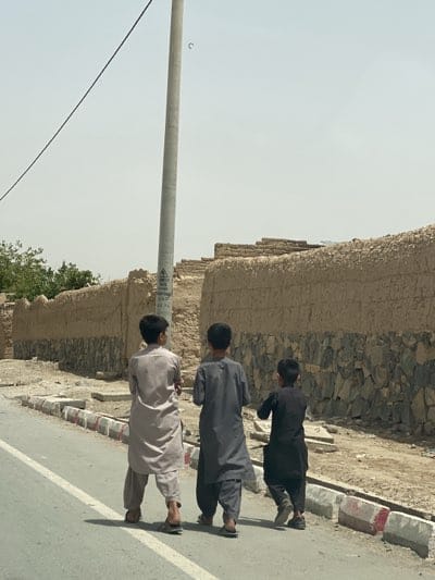 Boys in traditional dress walk Kandahar street