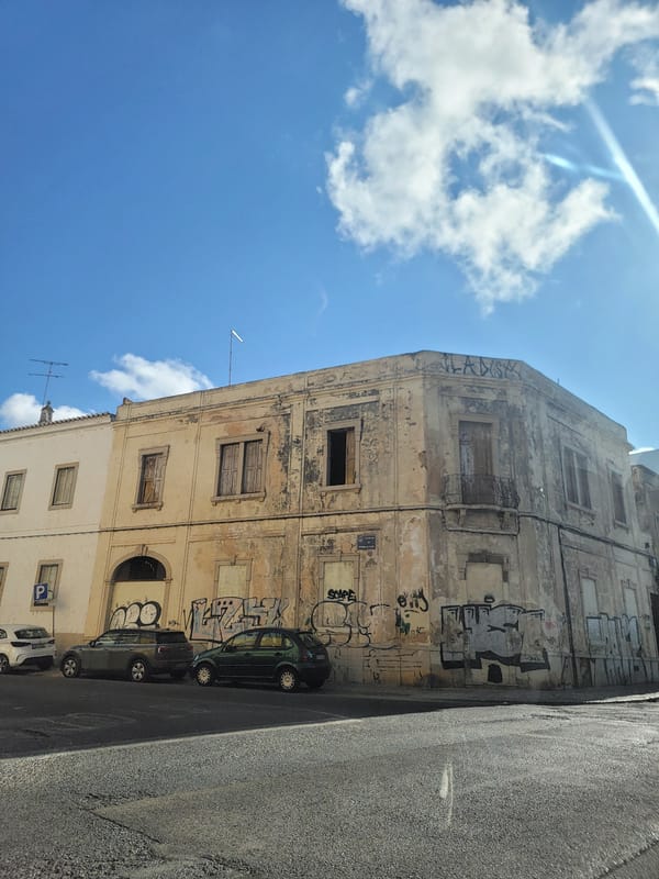 Street-level Faro: graffiti walls, parked cars, and local architecture