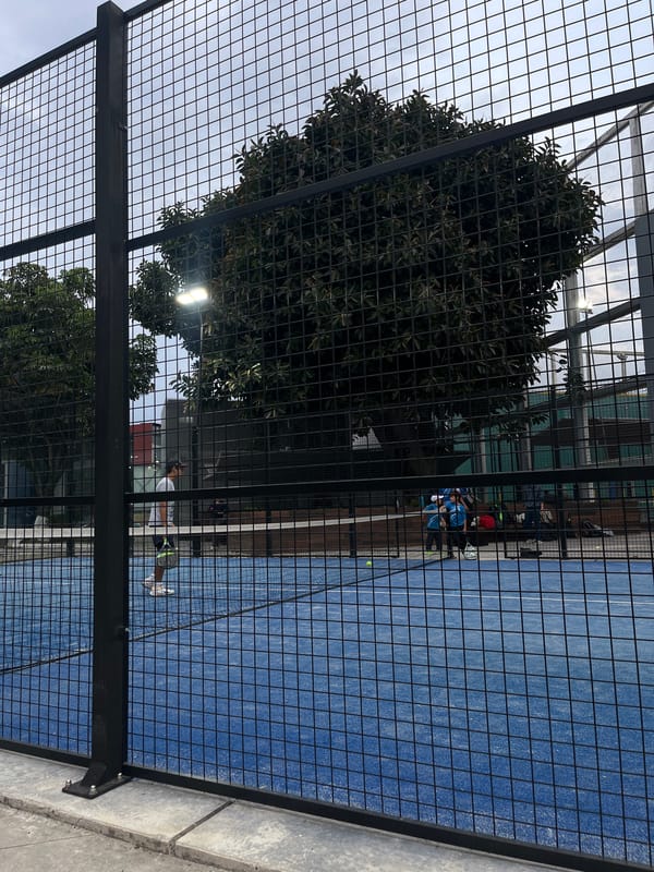 Late night paddle tennis player captured mid-swing on blue court