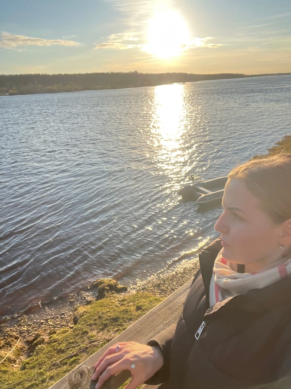Woman watches sunset by water in Riga, Latvia