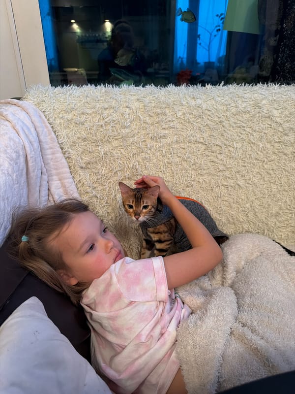 Girl relaxes with dressed Bengal cat on rug
