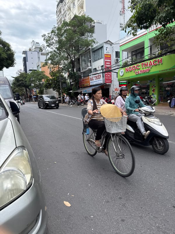 Nha Trang street traffic: cyclists and a waste collection motorcycle