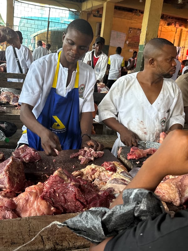 Two butchers work meat counter at indoor market