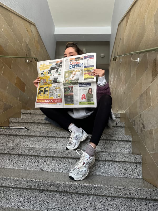Young person reads local newspaper on Kiel staircase