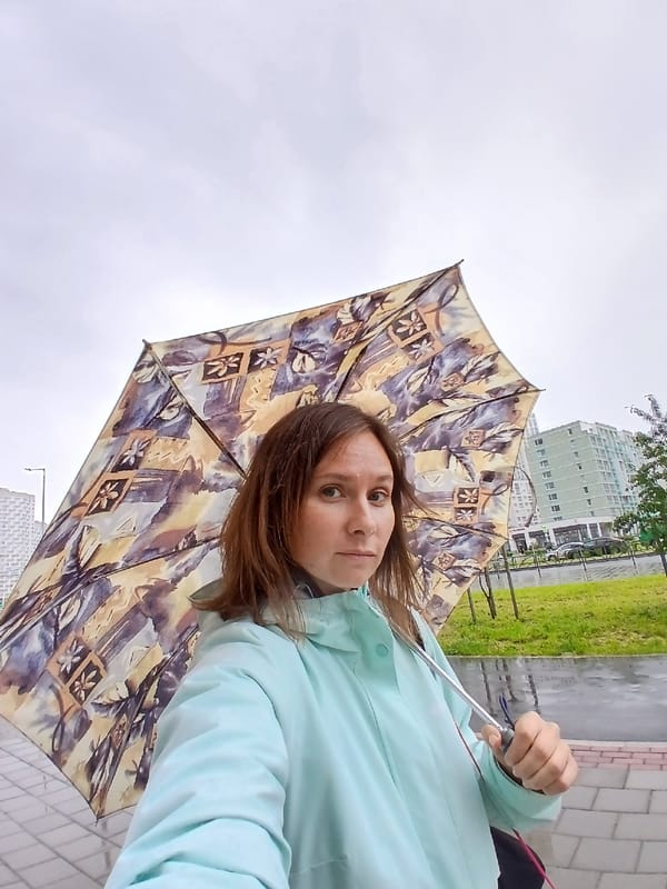 Rainy day street scene with umbrella and cyclist, Yekaterinburg