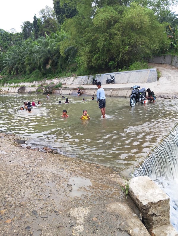 Children play in river near waterfall in Saweuk, Indonesia