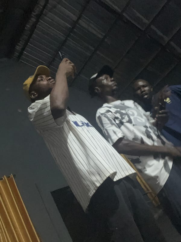 Community gathering in a metal-roofed hall with phones out