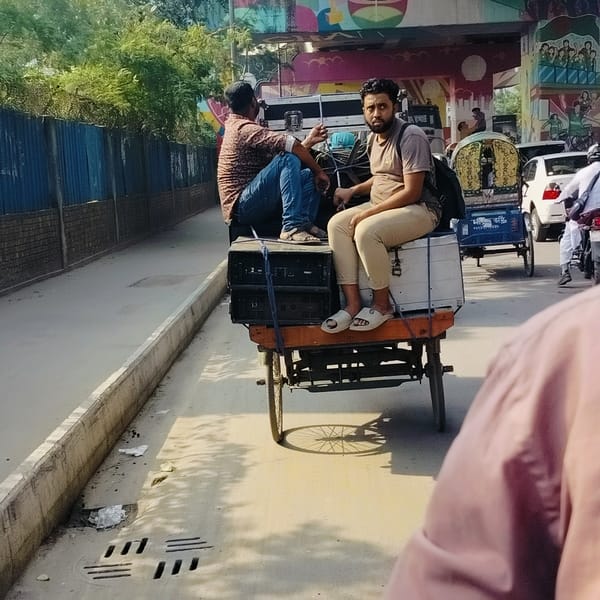 Two men ride decorated rickshaw in Dhaka streets