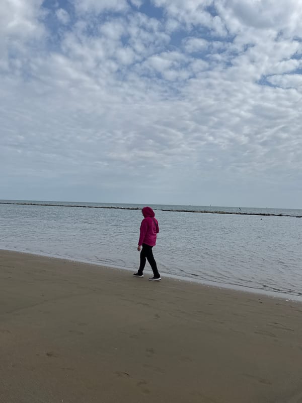 Beachgoers fish and stroll on overcast afternoon in Nettuno