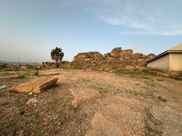 Two people overlook Jos settlement from rocky hilltop at sunset