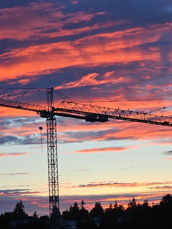 Construction crane silhouetted against a vivid Vancouver sunset