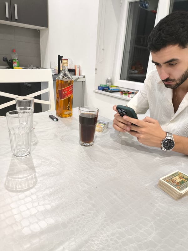 Man uses phone at table with whiskey, glasses
