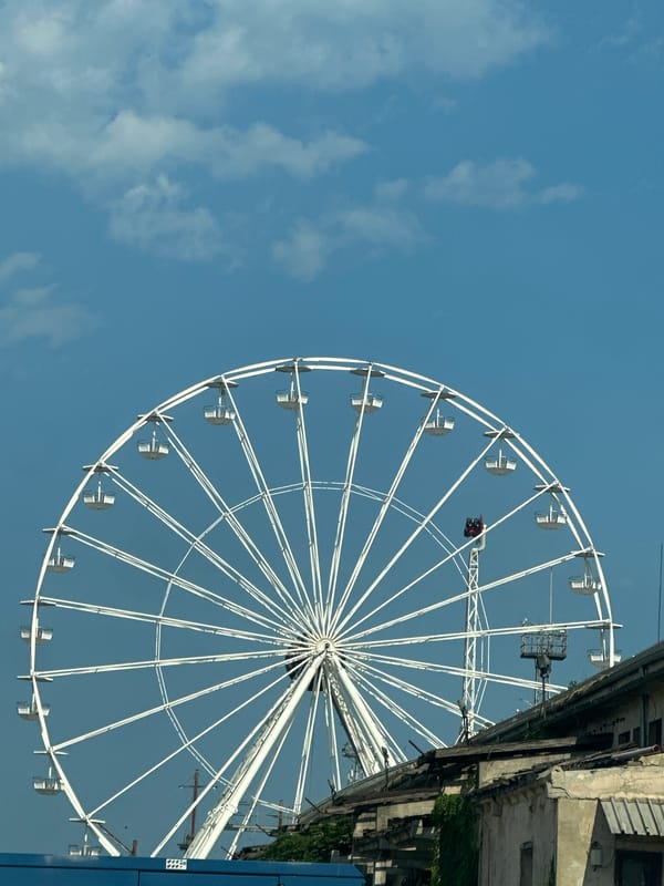 Ferris wheel and port cranes share the same waterfront skyline